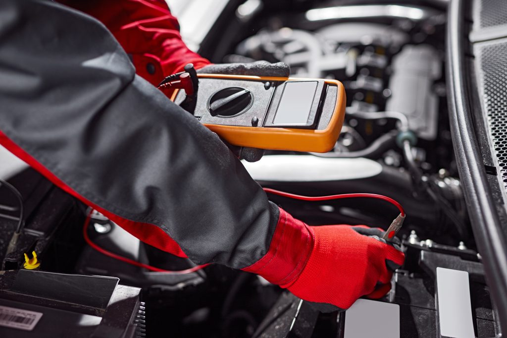 Crop male technician checking car battery